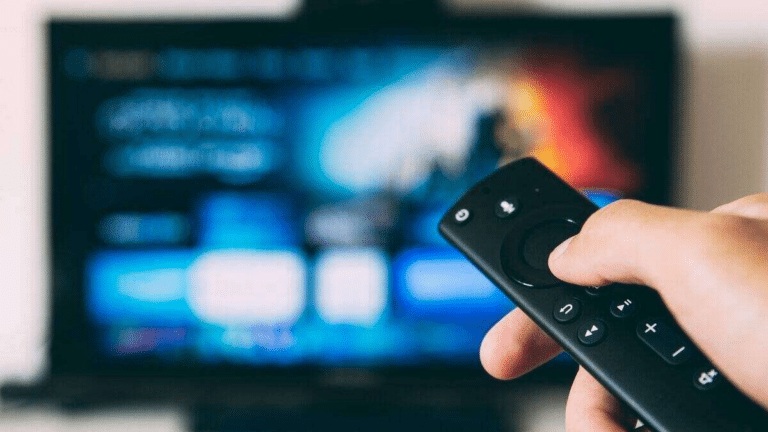 Una mano usa un telecomando davanti a un televisore