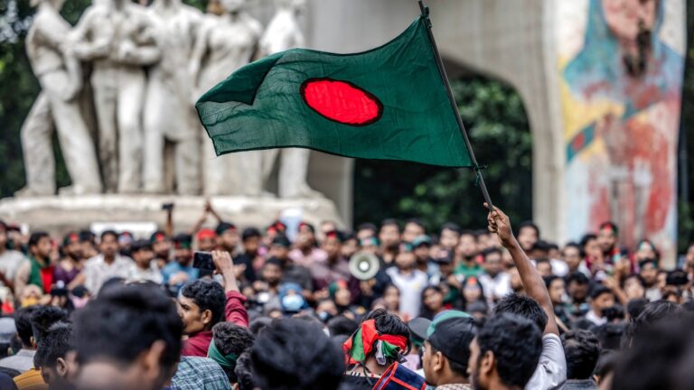Una folla di manifestanti con la bandiera del Bangladesh