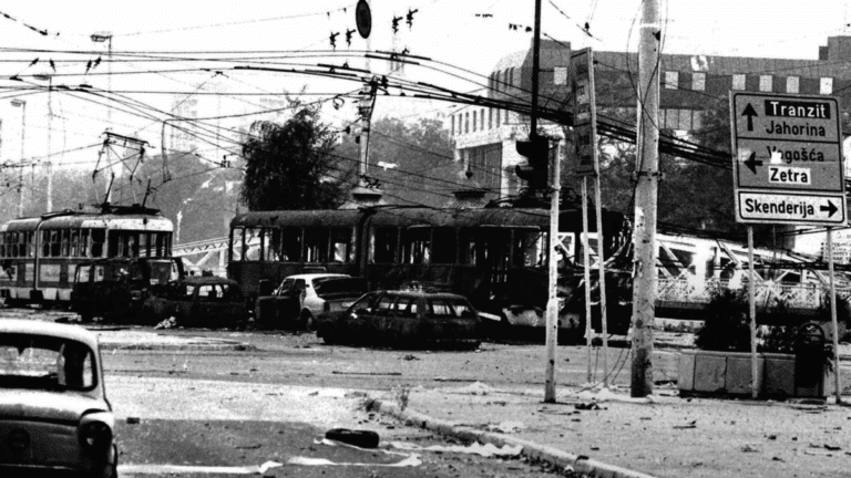 Fotografia in bianco e nero di una strada danneggiata con indicazioni per Travnik e altri centri bosniaci