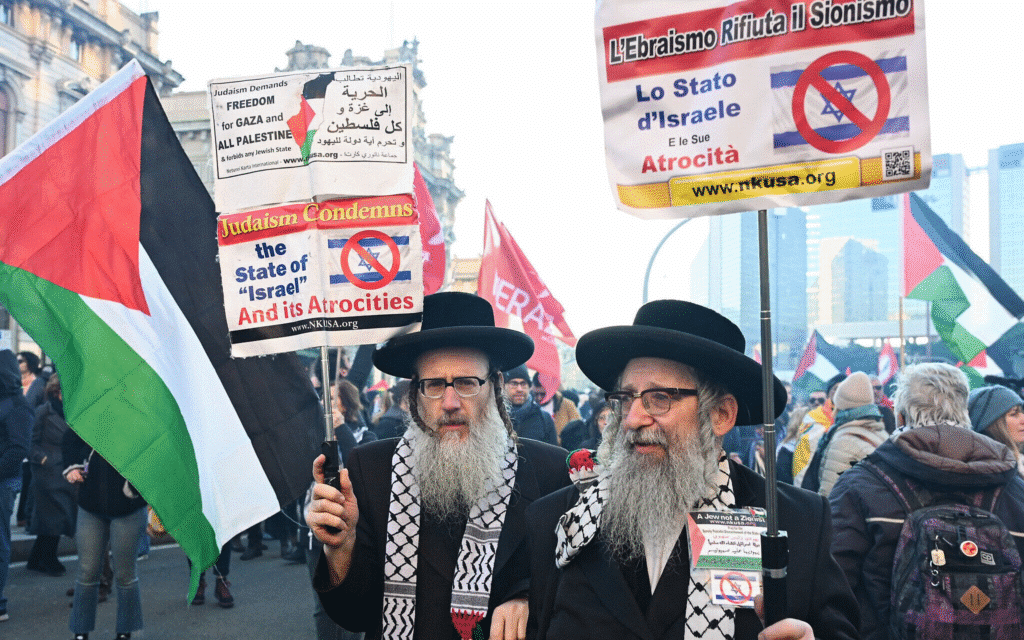 I due partecipanti alla manifestazione di Genova del 28 novembre 2025, recanti con sè cartelli in cui si fa riferimento al sito ufficiale del Neturei Karta.