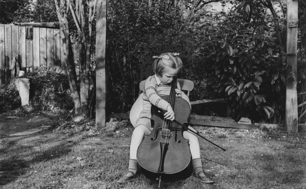 Jacqueline du Prè, da bambina, mentre suona il violoncello in giardino.