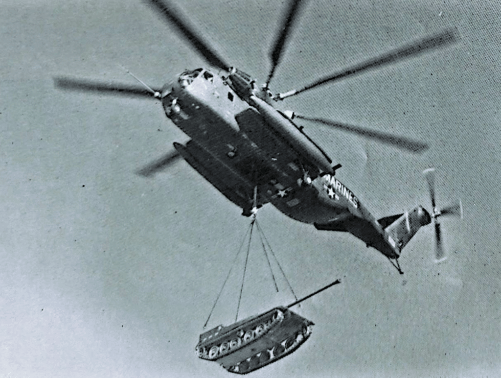Un Sikorsky CH-53E SUPER STALLION solleva un veicolo cingolato anticarro. Il CH-53E, diverso dai suoi precursori, ha tre motori turboshaft General Electric T64-GE-415.
